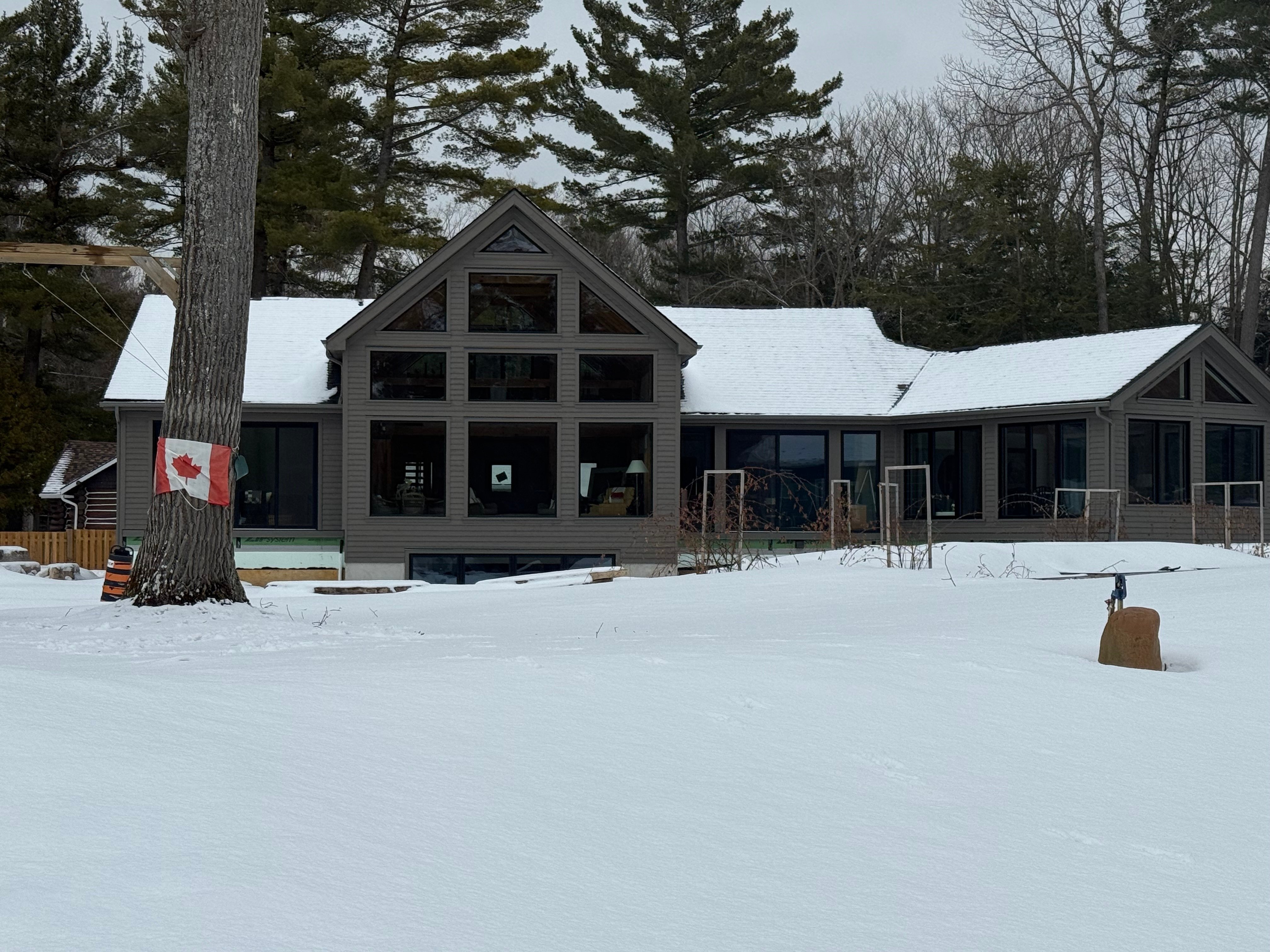 Customized Normerica Rocklyn timber frame home on Georgian Bay in winter, featuring a two-storey window wall and four-season sunroom addition